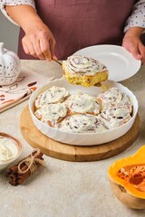 Step by step cooking pumpkin buns on light concrete background. Finished cinnabons in a round ceramic form. Recipes pumpkin, seasonal baking.