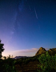 Night sky, full of stars and meteors, over a landscape