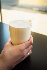 A woman is holding takeaway coffee in her hand in autumn.