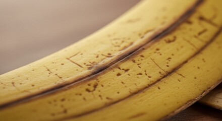 Close Up Yellow Banana Peel Showing Speckles on Wooden Surface