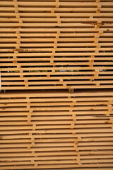 Stacked wooden planks with visible dark marks and rough edges, lumber material arranged for industrial drying and carpentry manufacturing process