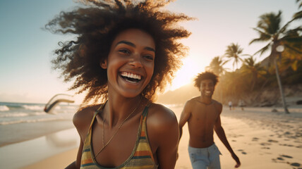 Happy cheerful young couple having fun running to the sea together on a tropical beach at sunset - concept about romantic vacation, honeymoon.