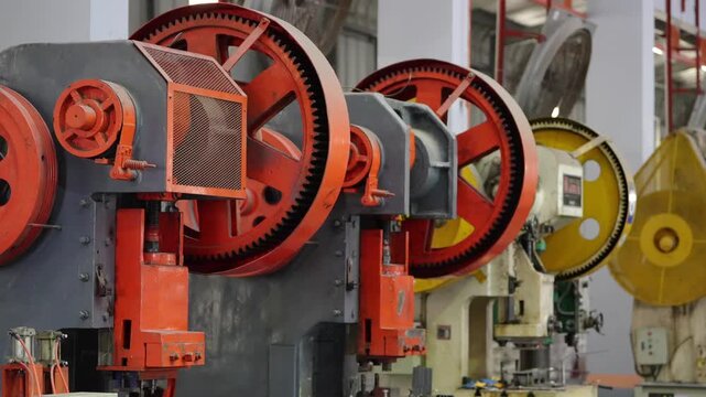 Industrial Metal Stamping Presses: A row of heavy-duty industrial metal stamping presses, with large, weathered gears and sturdy metal frames, stand ready for production in a factory setting.