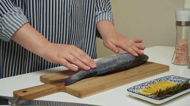 Female hands preparing the sea bass fish for cooking at home kitchen. Concepts of healthy eating and seafood