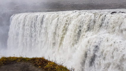 A powerful, wide torrent of water crashes down at Dettifoss waterfall in Iceland, filling the frame...