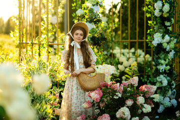 Beautiful young woman in vintage elegant dress posing among hydrangeas in a park