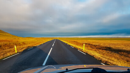 A point-of-view shot from a car driving on a straight, empty highway through vast golden plains...