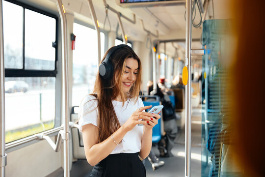 Young woman enjoying music on smartphone while commuting in public transport, modern lifestyle concept