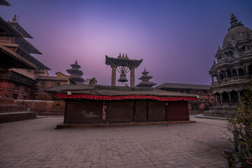 Magic view of Patan Durbar Square in Kathmandu, Nepal. Traditional Newari architecture with illuminated temples and purple sky. Historical UNESCO World heritage with cultural and architectural beauty.