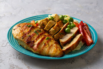 Grilled chicken breast slices served with mashed potatoes and vegetables.