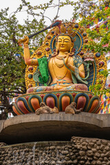 Vibrant Buddhist statue surrounded by natural elements with monkeys resting at the base in Kathmandu, Nepal. A unique scene combining spirituality, culture, tradition and wildlife.