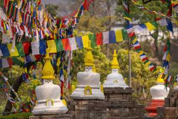 Colorful prayer flags and traditional Buddhist stupas in Swayambhunath area, known as monkey temple, Kathmandu, Nepal. Peaceful atmosphere and colorful flags reflecting Nepalese culture and religion.