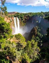 Naklejka premium Waterfall cascading through lush, rocky landscape
