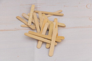 Wooden craft sticks pile on light background - natural popsicle sticks for DIY projects, handmade crafts, ice cream sticks