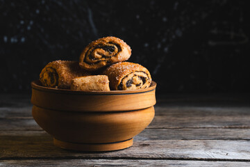 Biscuits with poppy seeds in wooden bowl on dark background.