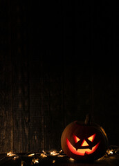 Halloween pumpkin with scary face on wooden background. Jack o lantern in the dark