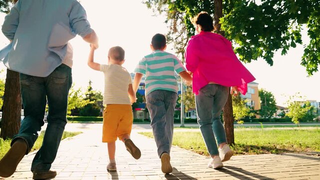 Parents children boys play running in city park summer. Happy family. Dad mom sons kids have fun run along city street. Concept of raising children. Family in city park. Happy people mother father son