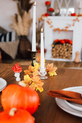 Autumn table setting with candles and pumpkins at a cozy indoor space during the fall season