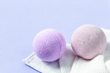 Colorful bath bombs resting on a towel against a soft purple background