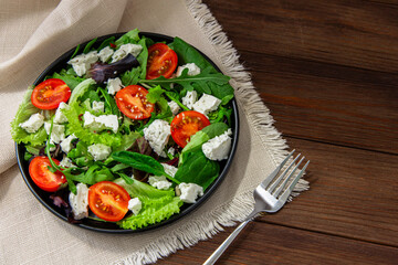Fresh green salad with tomatoes and cheese on a wooden table during daylight