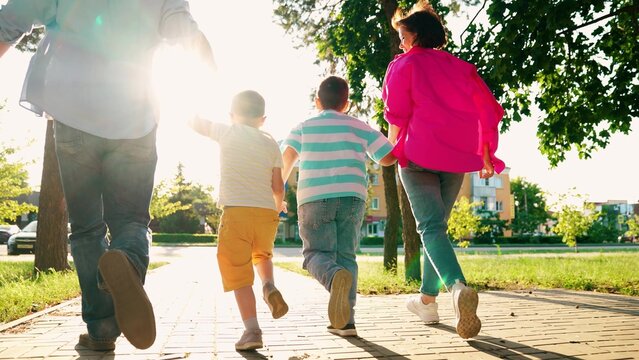 Parents children boys play running in city park summer. Happy family. Dad mom sons kids have fun run along city street. Concept of raising children. Family in city park. Happy people mother father son - Powered by Adobe