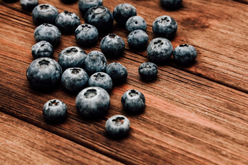 Fresh blueberries scattered on rustic wooden surface in natural light