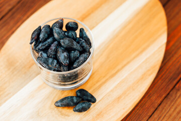 honeysuckle berries in a transparent glass bowl on a wooden table