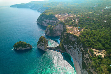 Cinematic aerial landscape shots of the beautiful island Diamond beach of Nusa Penida. Huge cliffs by the shoreline and hidden dream beaches with clear water.