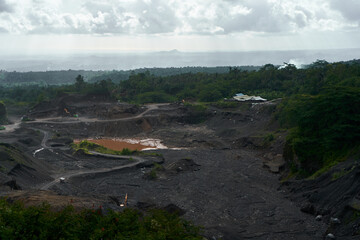 A stone quarry in Indonesia. Large equipment such as bulldozers and dump trucks are working on the site.