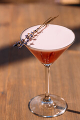 Pink cocktail with lavender sprig on wooden table