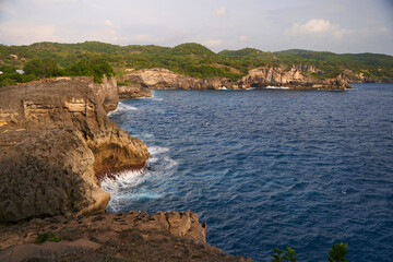 Cinematic aerial landscape shots of the beautiful island of Nusa Penida. Huge cliffs by the shoreline and hidden dream beaches with clear water and foaming wave.