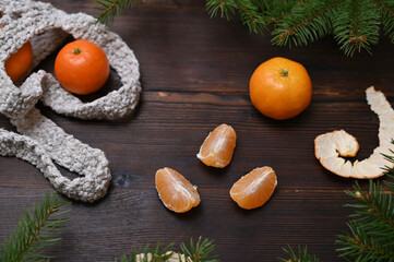 peeled tangerine slices and fir branches on wooden background close-up