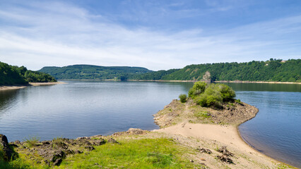 Small peninsula in the Bort-Les-Orgues reservoir in France under a partly cloudy sky