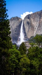 Majestic waterfall cascading down granite cliff, surrounded by lush forest