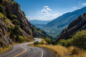 Fototapeta premium A beautiful winding road meanders through lush mountains under a bright blue sky showcasing natures splendor