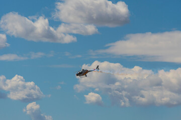 Helicopter flying with a long smoke trail in the sky during an airshow performance.