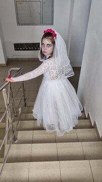A girl in a white dress and a veil, the image of a scary bride, a zombie,walks around the house, on Halloween