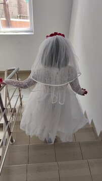 A girl in a white dress and a veil, the image of a scary bride, a zombie,walks around the house, on Halloween
