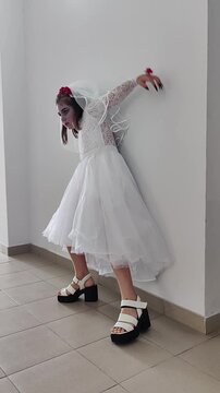 A girl in a white dress and a veil, the image of a scary bride, a zombie,walks around the house, on Halloween