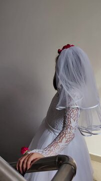 A girl in a white dress and a veil, the image of a scary bride, a zombie,walks around the house, on Halloween