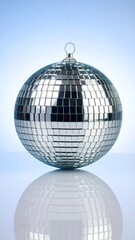 A reflective disco ball, perfectly round, rests serenely on a light blue surface, showcasing its mirrored, mosaic design.