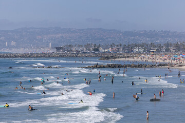 San Diego, California, USA - August 27, 2023: People enjoy the sand and surf of Ocean Beach on a hot day.