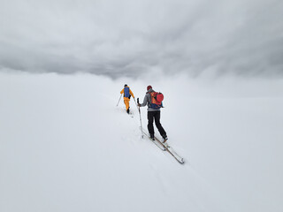 2 people ski touring into a cloud