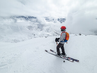 Single female skier overlooking a cloud covered valley in France