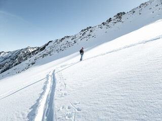 Single female ski tourer ascending in fresh snow