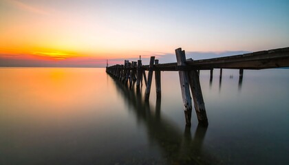 Obraz premium Sunrise over a weathered wooden pier