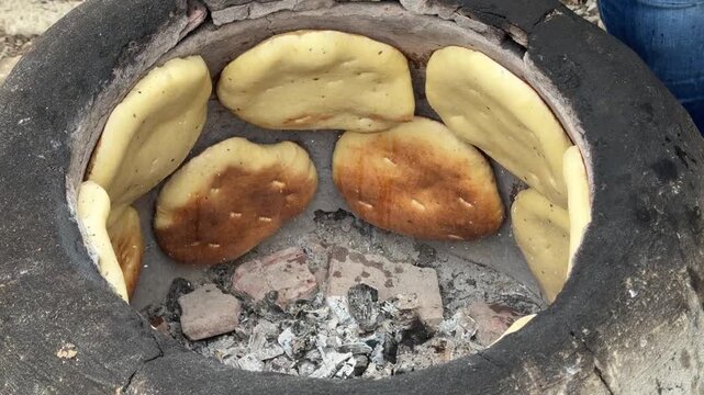 Woman cooking Traditional Tunisian flatbread (Tabouna) in a stone or clay oven called a Tabouna