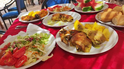 Set table with roasted chicken, vegetables, salad and watermelon