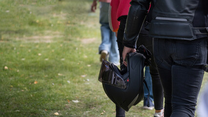 Biker holding helmet while walking outdoors