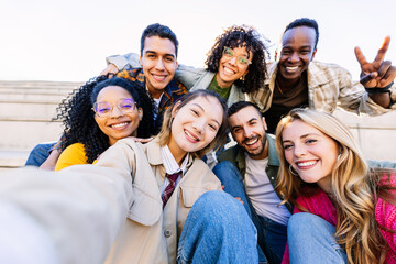 Happy multiracial students posing for a selfie together at the city street, enjoying youth, friendship, and community moments.